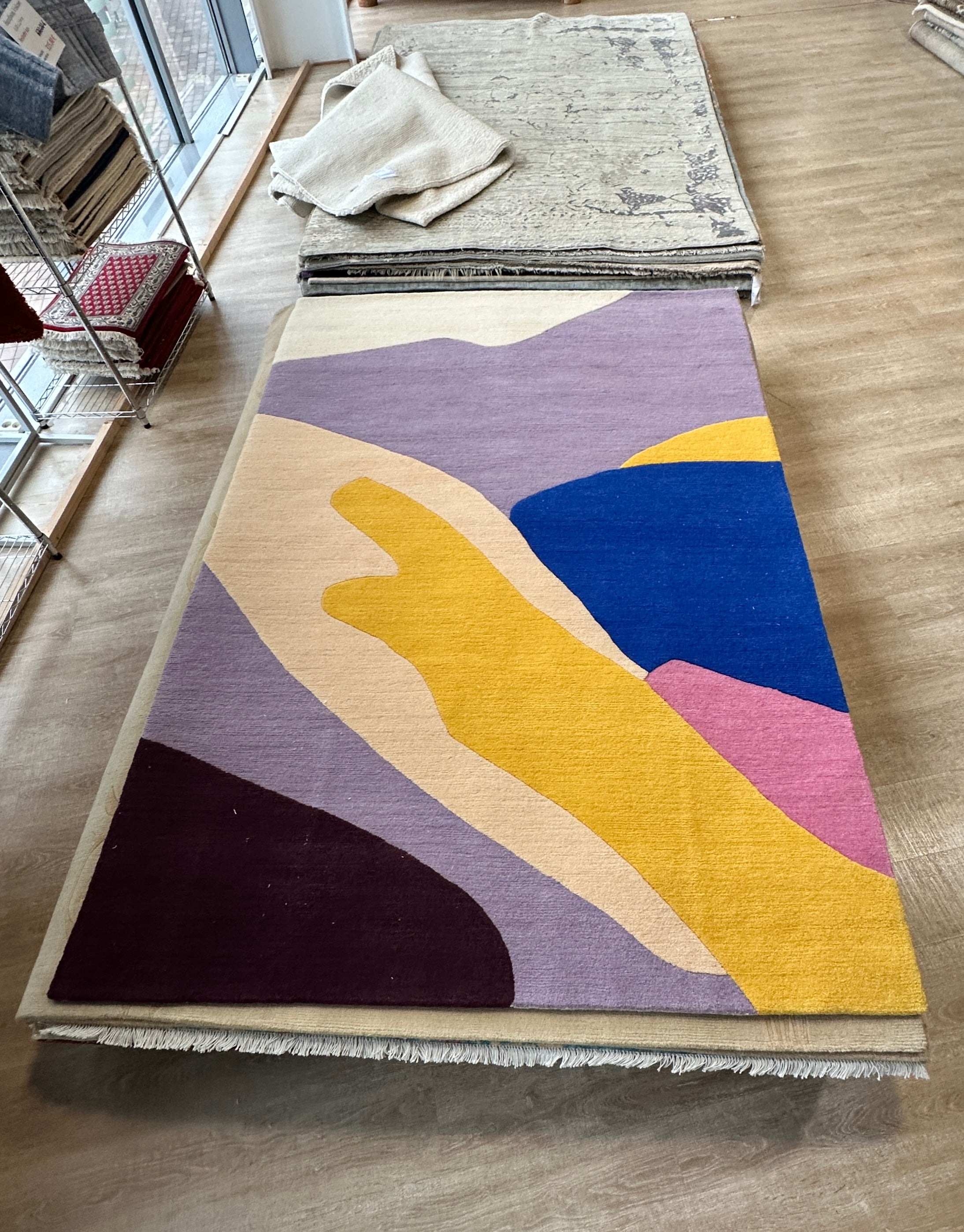 Contemporary abstract wool rug by Art of Meka shown in a rug showroom, hand-tufted design with bold organic color shapes